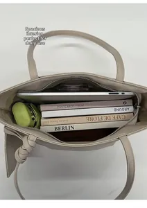 Draufsicht auf den geräumigen Innenraum der beigen Tragetasche mit Laptop und Büchern