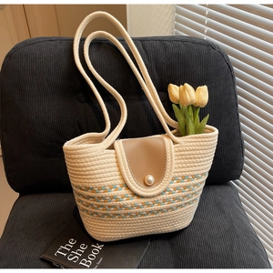 Detail of handwoven tote bag with colored stripes and pearl clasp on dark chair