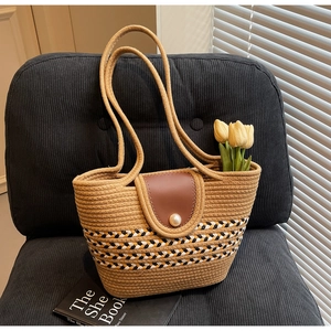 Detail of woven straw tote bag featuring pearl closure and geometric stripes on a chair