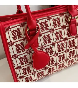 Dettaglio del motivo a maglia Doppia Felicità rosso sulla borsa con ciondolo a cuore
