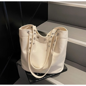 Close-up of ivory PU leather tote bag with silver metal eyelets and rivet detailing