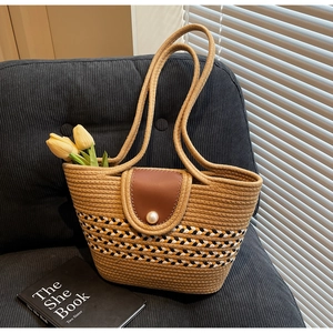Detail of straw woven tote bag featuring a leather flap and elegant pearl buckle closure