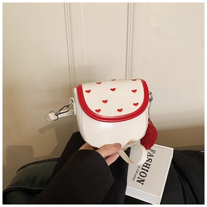 Dettaglio mini borsa bianca a tracolla con ricamo a cuore rosso e ciondolo a pompon