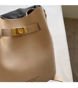 Close-up of cream white bucket bag with golden buckle and textured faux leather details