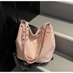 Detail of light pink hobo bag with silver metallic eyelets and rivets on smooth PU leather
