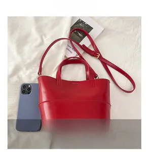 Detail of red leather tote bag showing compact size compared with a smartphone