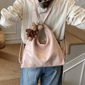 Detail of light pink soft leather tote with cute teddy bear charm on model's shoulder