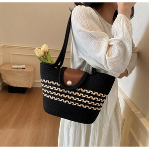 Close-up of black straw woven tote bag featuring a striped pattern and pearl buckle detail
