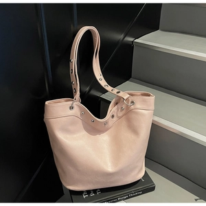 Detail of pink leather tote bag featuring silver metal eyelet grommets on the shoulder strap