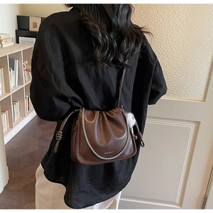 Detail of dark brown pleated cloud bag featuring silver chain and leather texture
