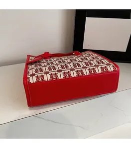 Dettaglio del tessuto jacquard Xi e finiture in pelle rossa sulla borsa tote da sposa