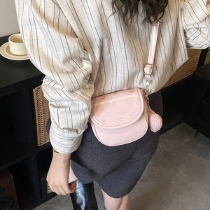 Borsa a tracolla rosa chic con motivi a cuore e ciondolo pompon indossata da una modella