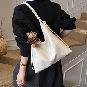 Detail of white large-capacity tote bag with cross-stitch design and brown plush bear charm