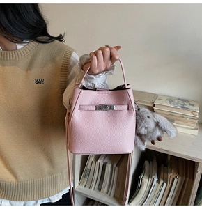 Detailed view of pink pebble leather bucket bag with metal lock and rabbit fur charm