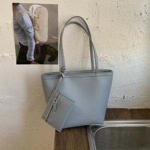Detail of grey-blue tote bag featuring litchi grain texture and matching mini zipper pouch