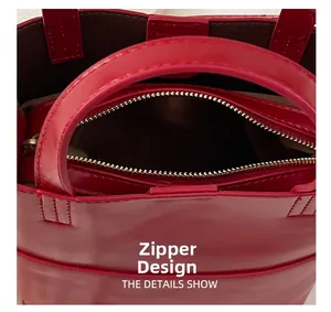 Close-up of a red oil wax leather bucket bag showing dual handles and zipper closure