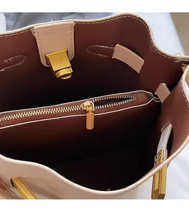 Detail showing the brown interior lining and smooth gold zipper of the beige bucket bag