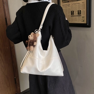 White PU leather tote bag with brown bear charm shown on model in a retro setting