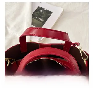 Detailed view of red glossy tote bag with golden zippers and handles on a white background