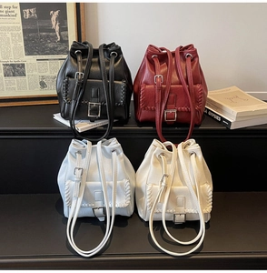 Detail view of bucket bags in four colors with braided flap and metal buckle accents
