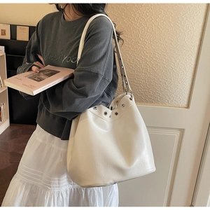 Close-up of white leather tote bag featuring stylish silver metal eyelets and rivets