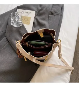 Detail view of the spacious inner compartment of the beige bucket bag on a grey blazer
