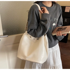 Detail of cream oversized tote bag with silver eyelets and smooth leather texture