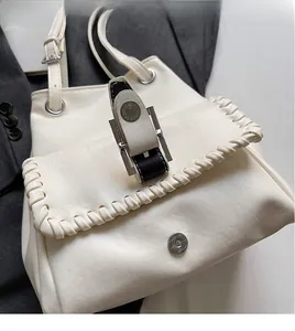 Detail of white leather bucket bag with braided edges and silver magnetic closure