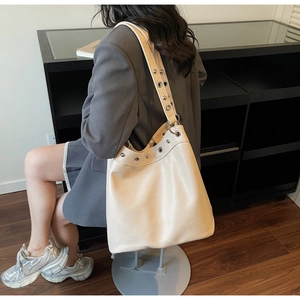 Detail of silver rivets and eyelets on a cream punk-style oversized tote bag