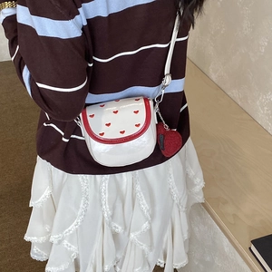 Dettaglio della mini borsa a tracolla bianca con ricami a cuore e ciondolo peluche