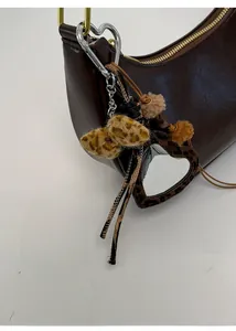 Détail d'un sac en cuir marron avec pendentifs cœur léopard et finitions dorées chic