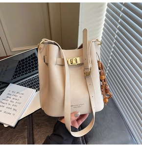 Détail du sac seau crème avec fermoir rotatif doré et pendentif rétro en perles de bois