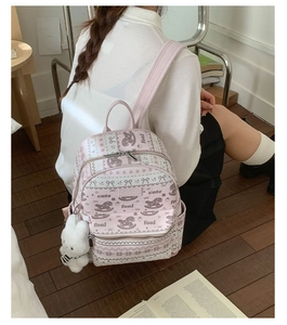 Detail of pink backpack featuring cute pony prints and a white plush bunny charm