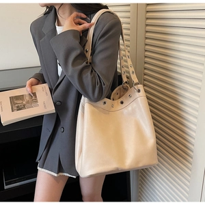Detailed shot of beige PU leather tote bag featuring stylish silver metal eyelet decorations