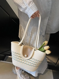 Handwoven straw tote bag with brown leather flap and large pearl buckle for beach vacations