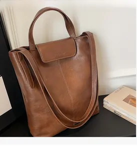 Détail d'un grand sac cabas marron vintage avec doubles poignées et logo embossé