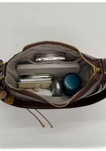 Vue intérieure du sac en cuir marron montrant sa grande capacité et sa poche zippée