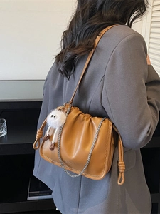 Brown pleated cloud crossbody bag with silver chain and cute plush monster charm