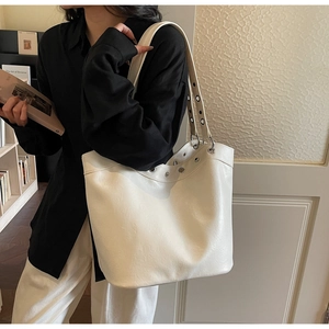 Detail of white leather tote bag with silver metal eyelets and textured finish