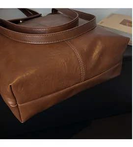 Gros plan d'un sac cabas marron montrant la texture du cuir plissé vintage et les coutures