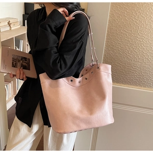 Detail of light pink leather tote bag with silver metal eyelets and thin shoulder straps