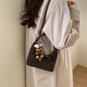 Detail of dark brown leather hobo bag with contrast stitching and decorative charm