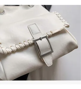 Detailed view of the woven edge stitching and silver buckle on the cream leather bucket bag