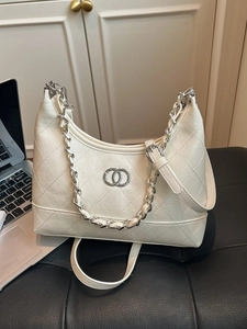 Sac sous le bras blanc matelassé avec chaîne argentée sur un tabouret en cuir noir