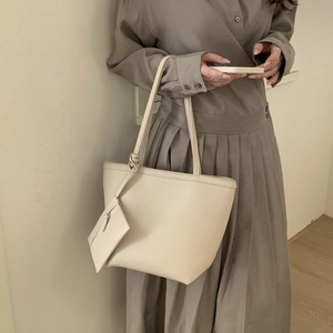 Detail of off-white lychee grain leather tote bag featuring a knotted handle and small pouch