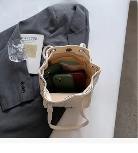 Spacious interior of beige bucket bag showing compartments with phone and wallet inside