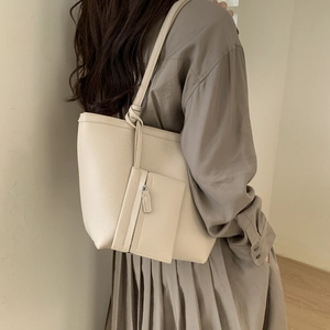 Macro detail of creamy white tote bag showing soft lychee texture and inner pouch pouch