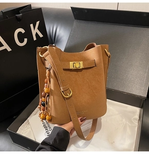 Détail du sac seau vintage caramel avec breloque en perles de bois et fermoir doré