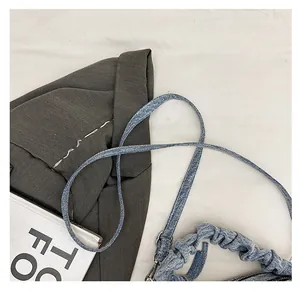 Detailed shot of comfortable denim shoulder strap and pleated handle on fashion handbag