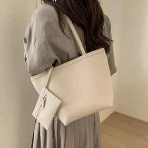 Detailed view of beige pebble leather tote bag with shoulder straps and a matching mini pouch